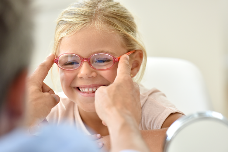 little girl at the optician trying different eyeglasses